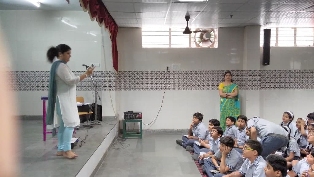 School hall session with students seated on the floor
